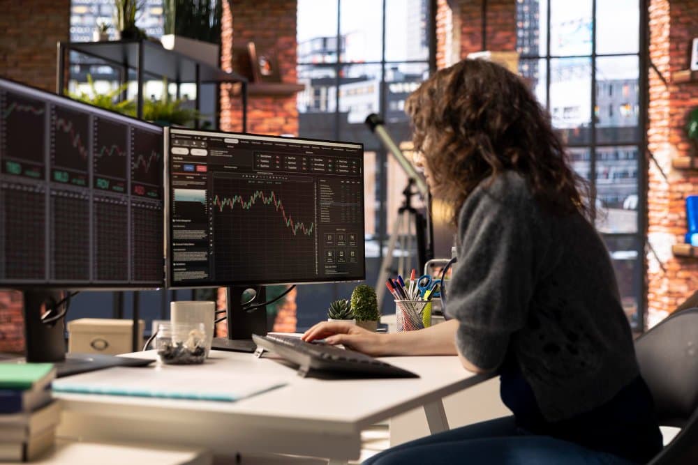 Trader analizando gráficos de mercado en múltiples pantallas